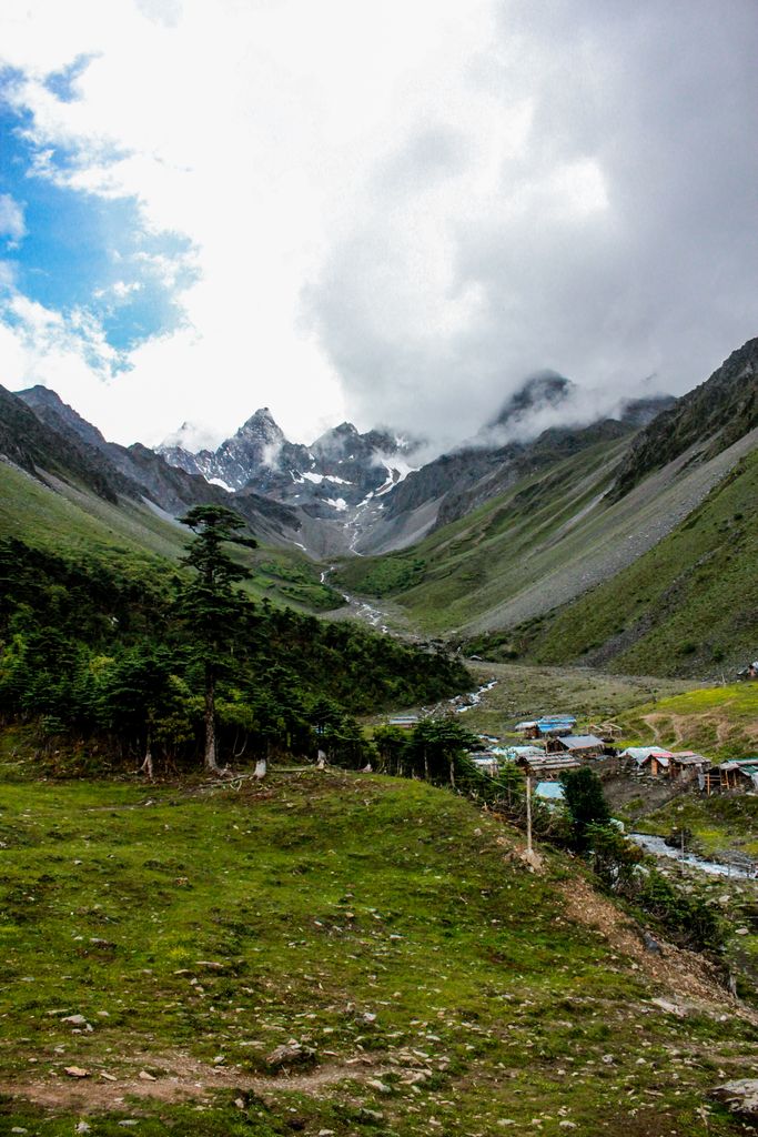 Breathtaking view of a lush mountain valley with dramatic clouds above.