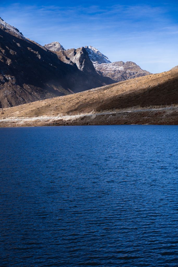 Stunning view of a tranquil lake surrounded by rugged mountains under a clear blue sky in Arunachal Pradesh, India.